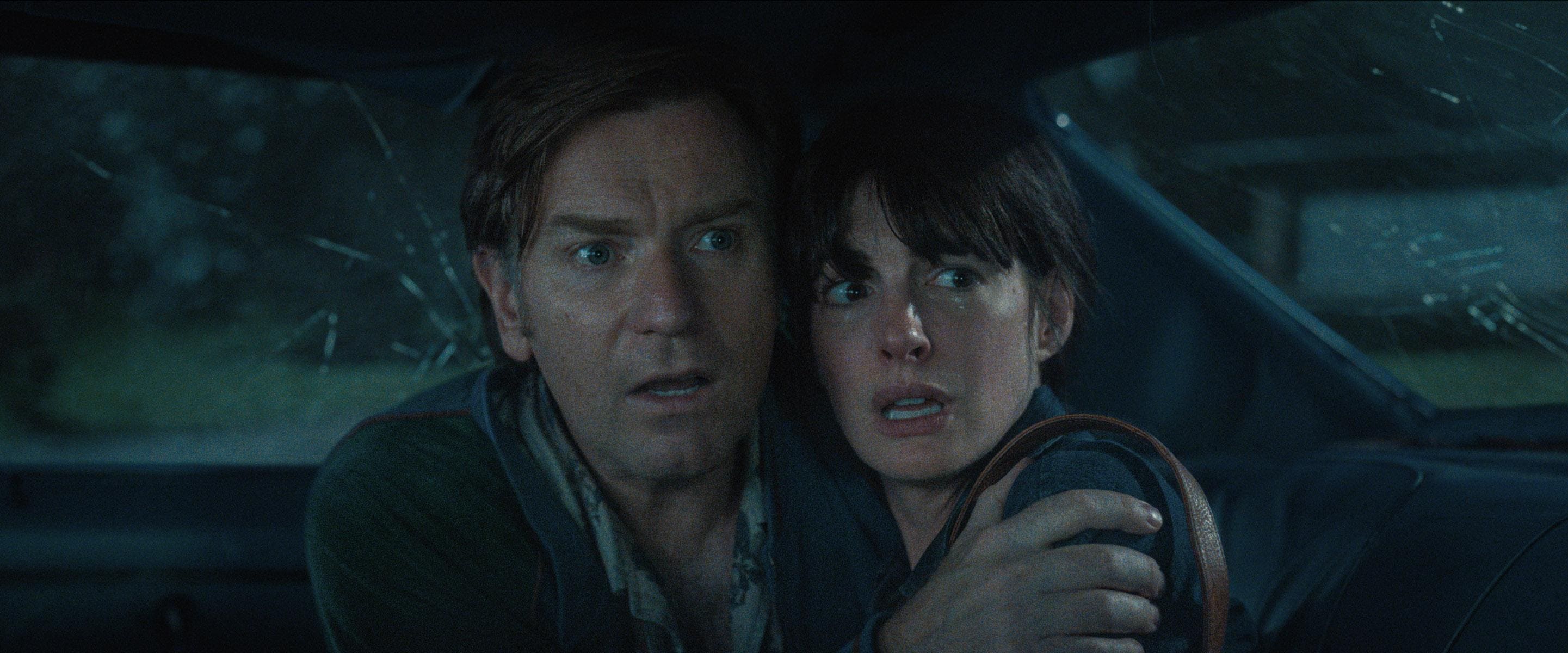 Greg e Denise Platt (Ewan McGregor e Anne Hathaway) se abraçam assustados dentro de um carro enquanto observam uma ameaça do lado de fora no filme O Fim da Rua.