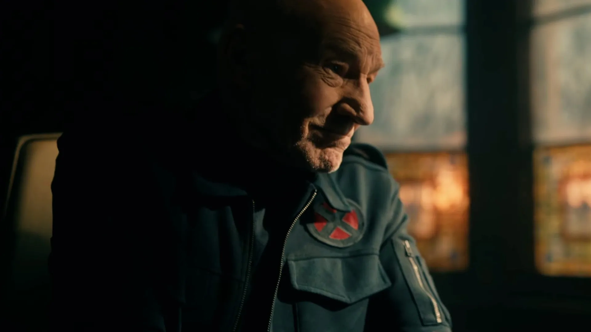 Professor Charles Xavier (Patrick Stewart) sorrindo, com uma jaqueta com o símbolo dos X-Men, em Vingadores: Doutor Destino (2026)