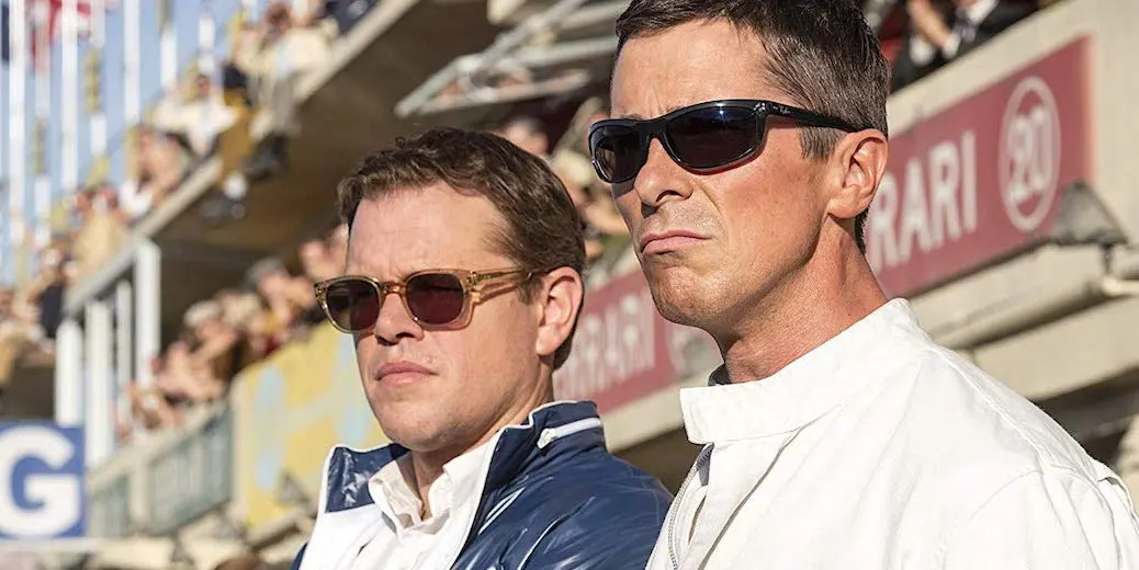 Carroll Shelby (Matt Damon) e Ken Miles (Christian Bale) de óculos escuros, observando a pista durante uma corrida