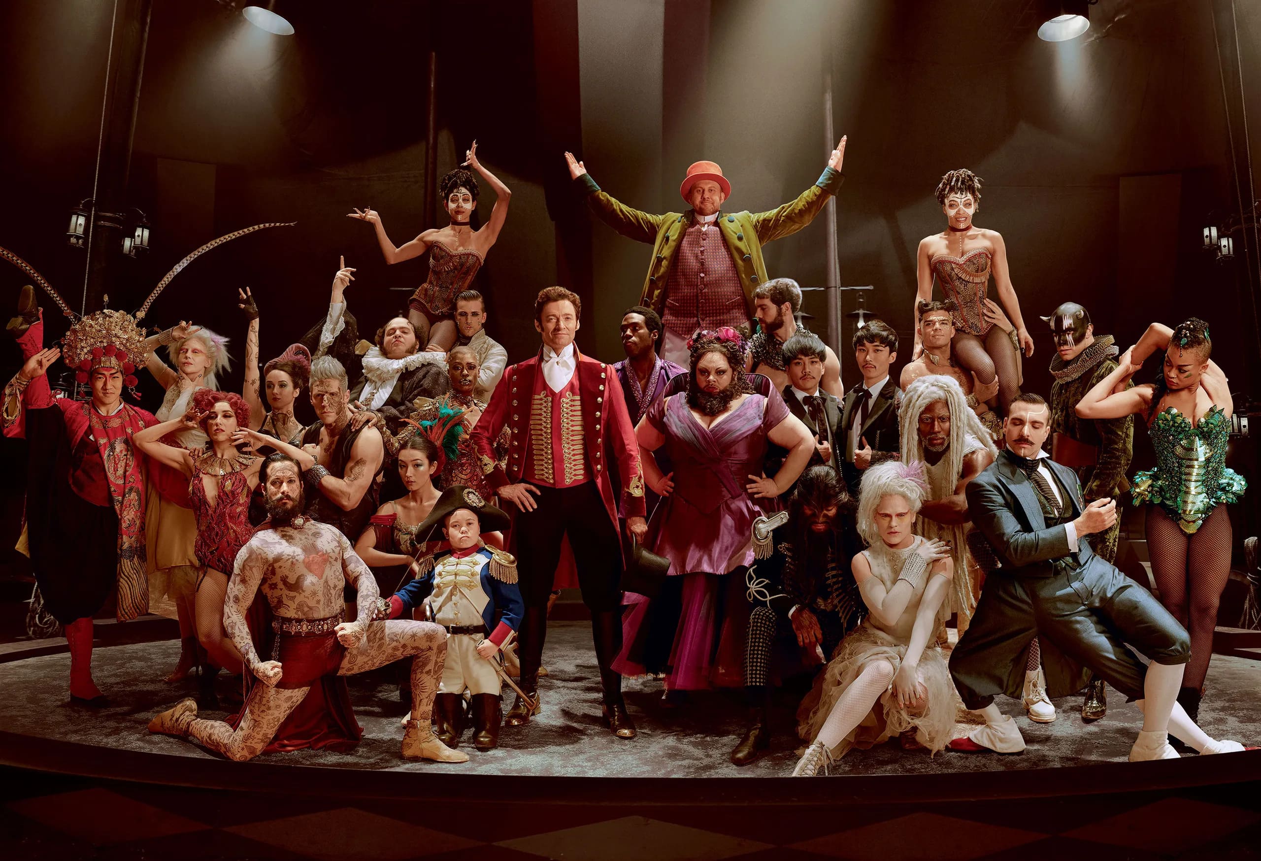 Imagem do filme O Rei do Show, com o elenco reunido em um palco sob luzes de teatro com poses performáticas e figurinos inspirados no circo do século 19.