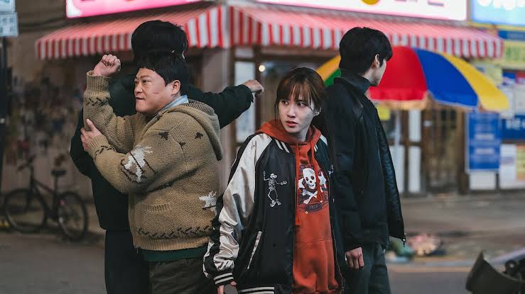 Eun Chae-ni (Park Eun-bin) observa enquanto Son Kyung-hoon (Choi Dae-hoon) e Kang Ro-bin (Im Seong-jae) brigam ao fundo, com Lee Un-jeong (Cha Eun-woo) por perto, em cena de Os SUPERtontos.