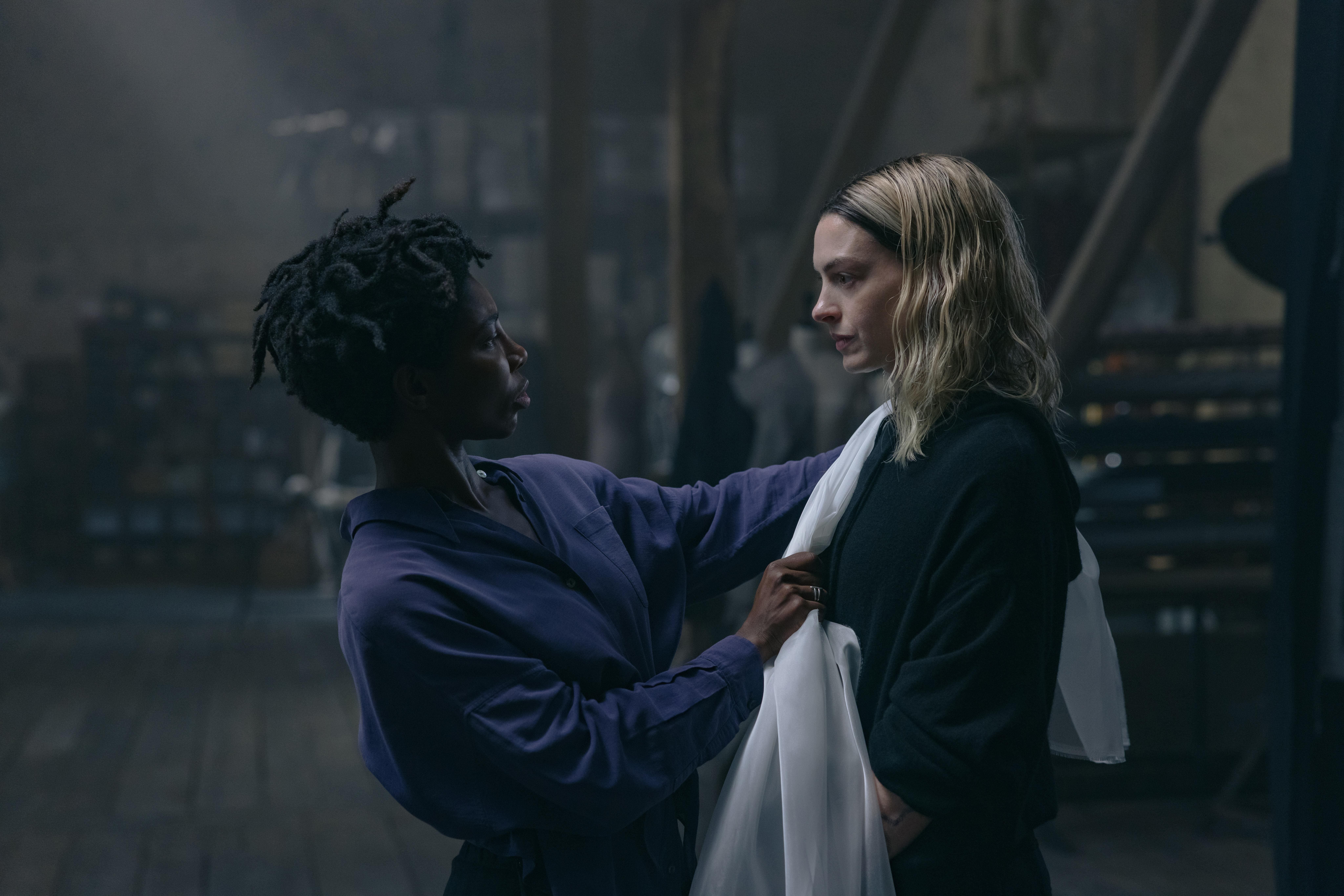 Sam Anselm (Michaela Coel) segura tecido branco sobre roupa de Mother Mary (Anne Hathaway) enquanto as duas se encaram em um ambiente escuro, em uma cena dramática do filme Mother Mary (2026).